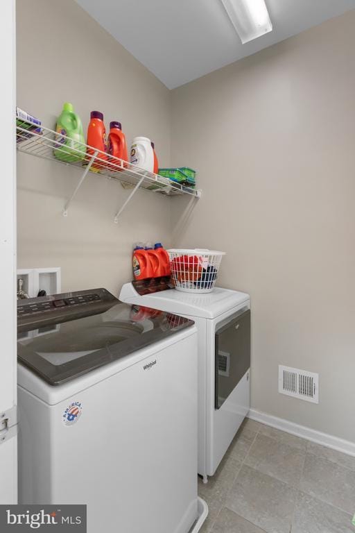 laundry area with laundry area, visible vents, baseboards, and separate washer and dryer