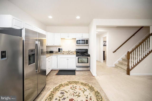 kitchen with white cabinetry, sink, light stone counters, and appliances with stainless steel finishes