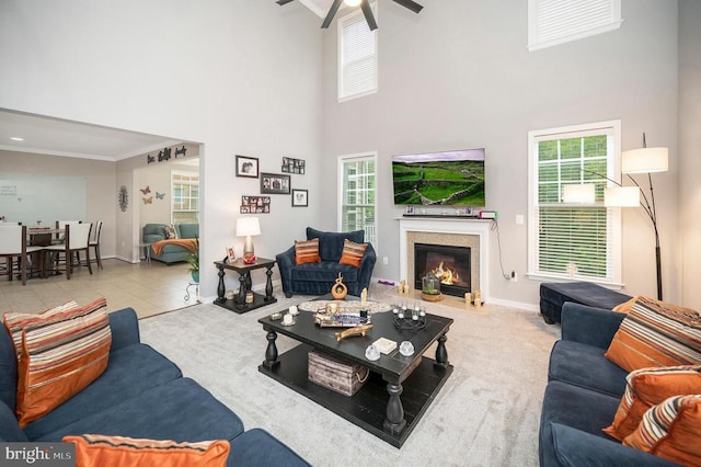 tiled living room featuring crown molding, a high end fireplace, plenty of natural light, and a towering ceiling