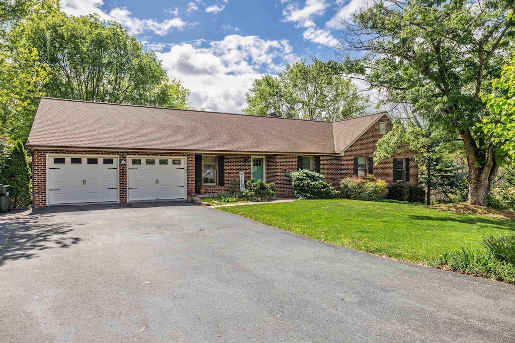 ranch-style house featuring a front lawn, driveway, a garage, and brick siding