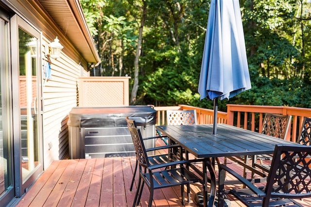 wooden deck with outdoor dining area and a hot tub