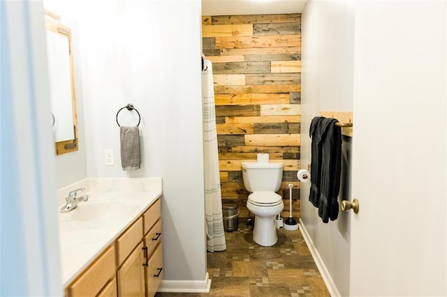 full bath with baseboards, vanity, toilet, and wooden walls