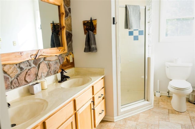 bathroom with a sink, a shower stall, toilet, and double vanity