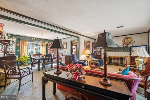 living room with a brick fireplace, crown molding, and a chandelier