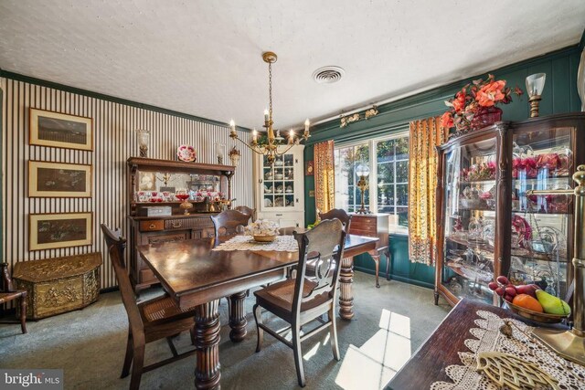 carpeted dining space featuring crown molding and a chandelier