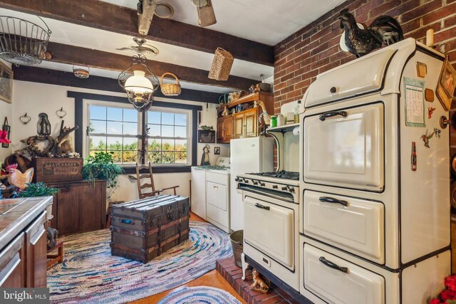 kitchen featuring range, tile countertops, washer and dryer, brick wall, and beam ceiling