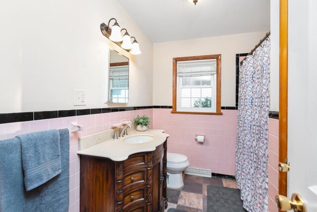 bathroom with vanity, tile walls, and toilet