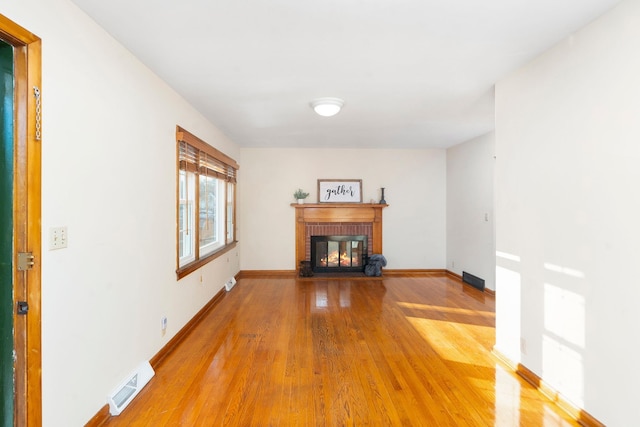 unfurnished living room with a brick fireplace and wood-type flooring