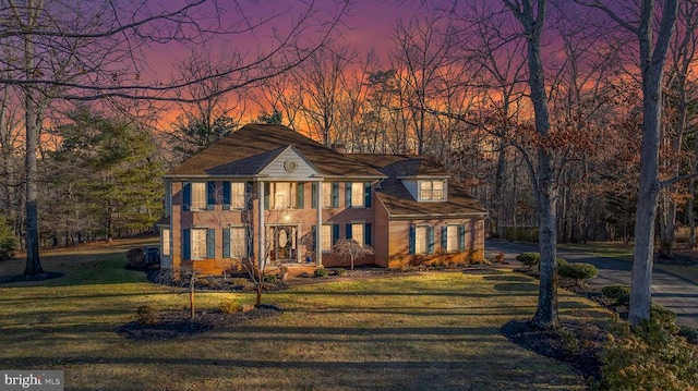 view of front of home with brick siding and a lawn