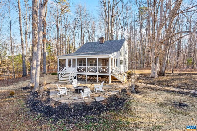 view of front of property featuring a patio, roof with shingles, a chimney, stairs, and a fire pit