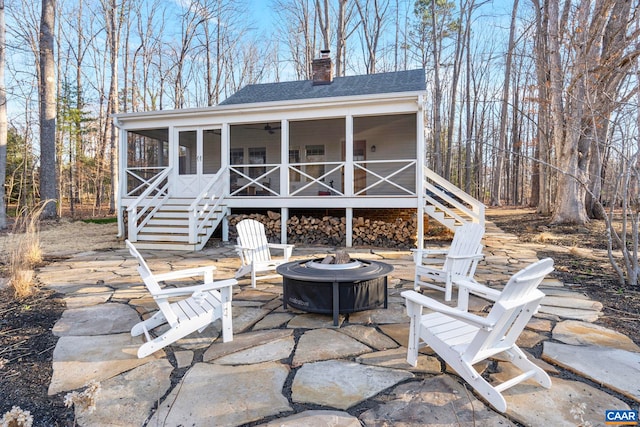 view of patio / terrace with a fire pit, stairs, ceiling fan, and a sunroom