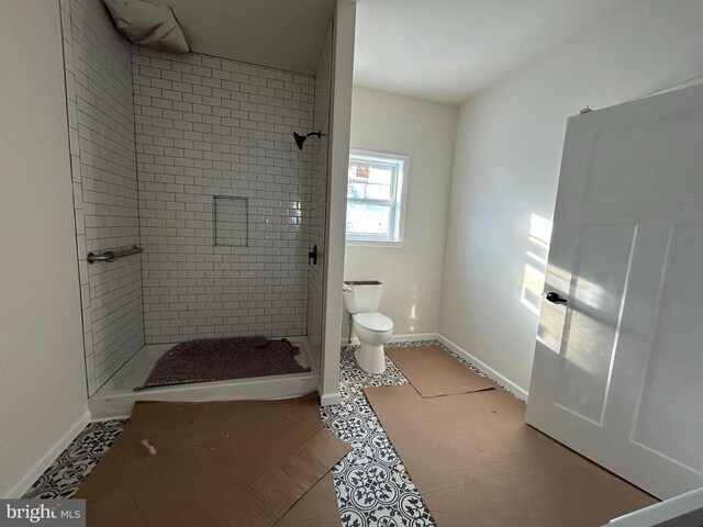 bathroom with a tile shower and toilet