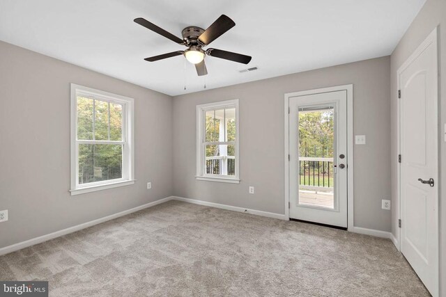 spare room with a healthy amount of sunlight, light colored carpet, and ceiling fan