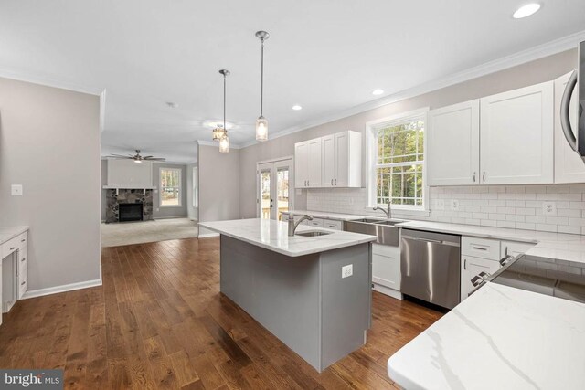 kitchen featuring pendant lighting, stainless steel dishwasher, a kitchen island with sink, and white cabinets