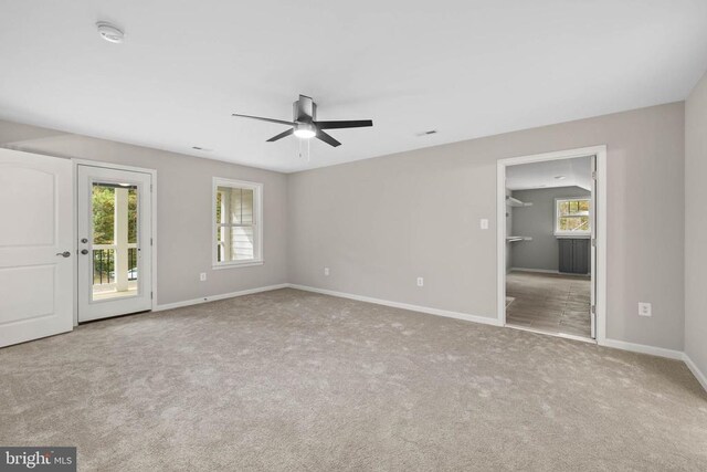 carpeted spare room featuring plenty of natural light and ceiling fan