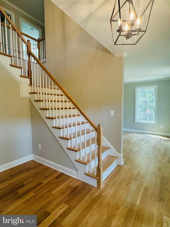 staircase featuring baseboards, an inviting chandelier, wood finished floors, and ornamental molding