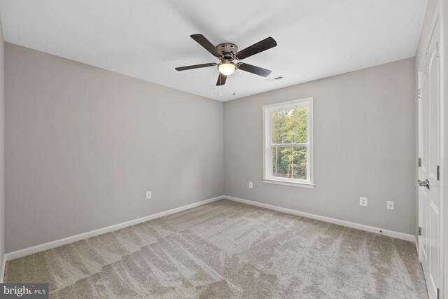 carpeted spare room featuring ceiling fan