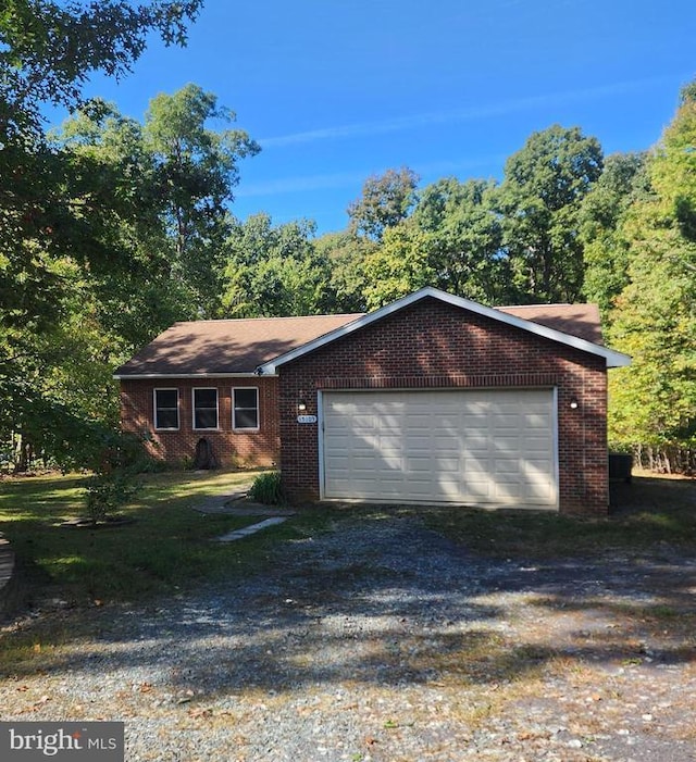 single story home with driveway, brick siding, and an attached garage