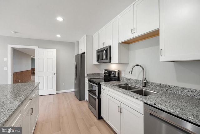 kitchen with recessed lighting, white cabinets, a sink, light wood-style flooring, and stainless steel appliances
