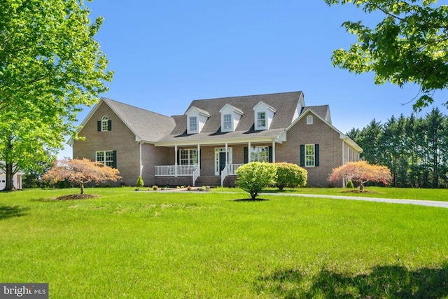 cape cod-style house with brick siding, covered porch, and a front yard