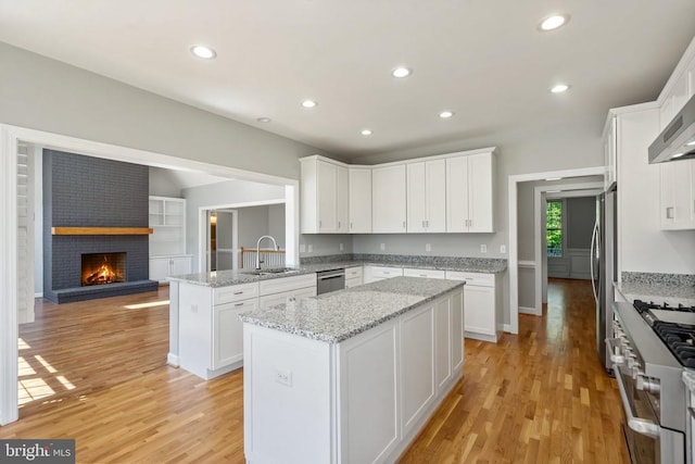 kitchen featuring a sink, light wood finished floors, appliances with stainless steel finishes, and white cabinetry