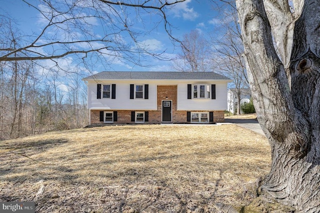 split foyer home featuring brick siding and a front lawn