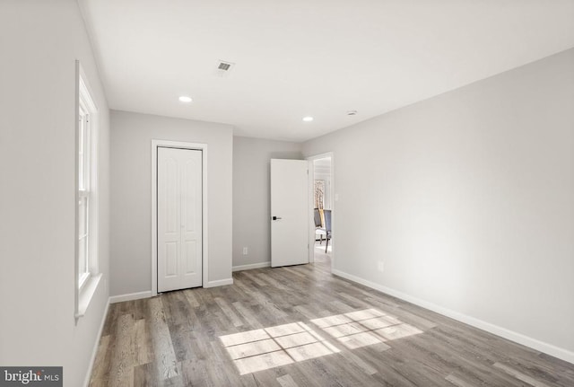 unfurnished bedroom with visible vents, recessed lighting, wood finished floors, and baseboards