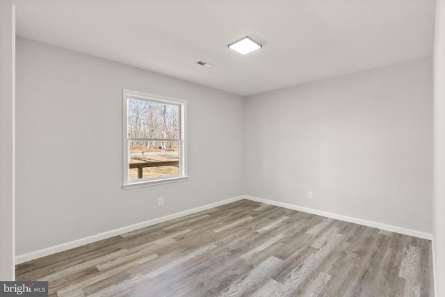 unfurnished room featuring visible vents, wood finished floors, and baseboards