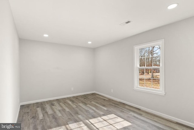 empty room featuring visible vents, recessed lighting, baseboards, and wood finished floors