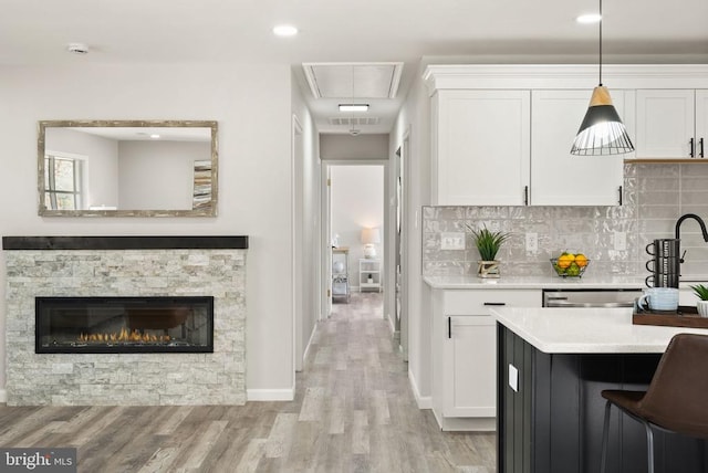 kitchen with decorative backsplash, white cabinetry, light countertops, and light wood-type flooring