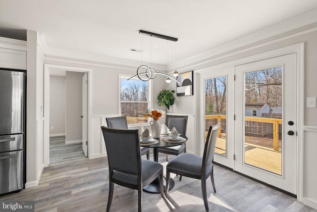 dining area with light wood finished floors, visible vents, and crown molding