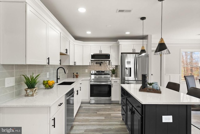 kitchen featuring white cabinetry, dark cabinets, appliances with stainless steel finishes, and a sink