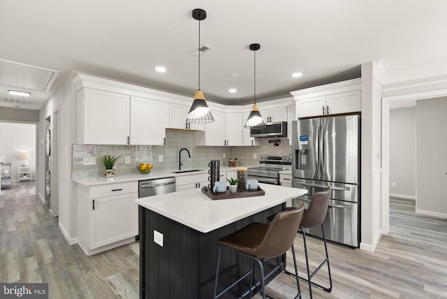 kitchen featuring light countertops, decorative backsplash, appliances with stainless steel finishes, white cabinetry, and a sink