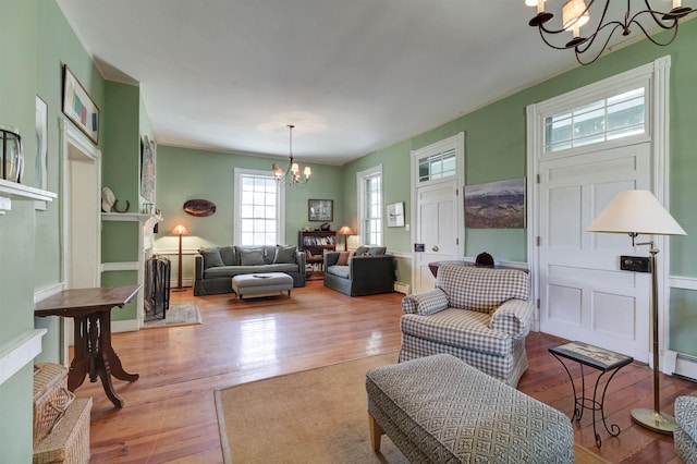 living room featuring ornamental molding, an inviting chandelier, and light hardwood / wood-style floors