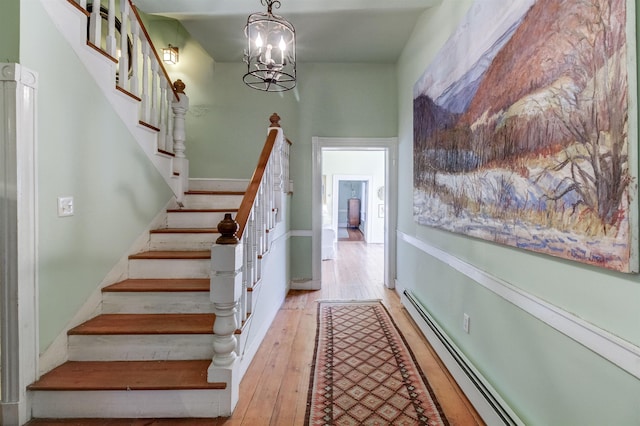 stairs with an inviting chandelier, hardwood / wood-style floors, and baseboard heating