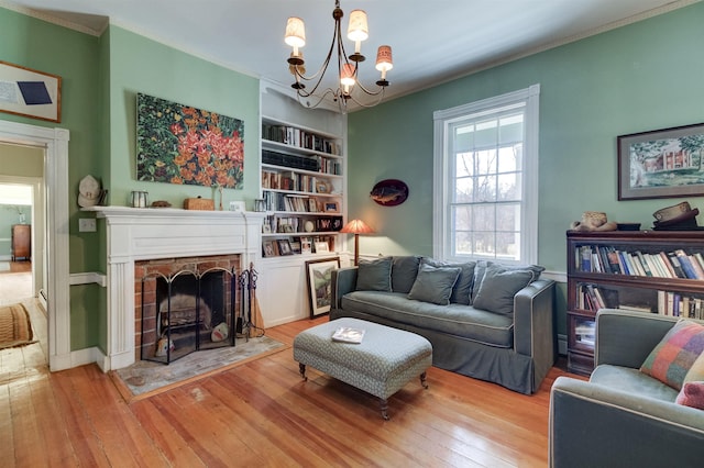 living room featuring crown molding, an inviting chandelier, built in features, and light wood-type flooring