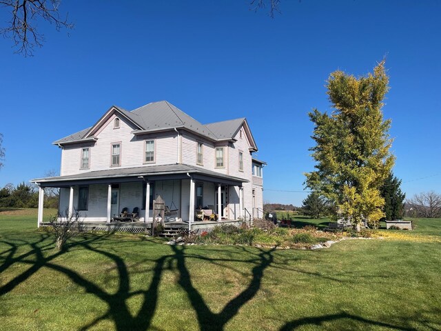 back of house featuring a yard and covered porch