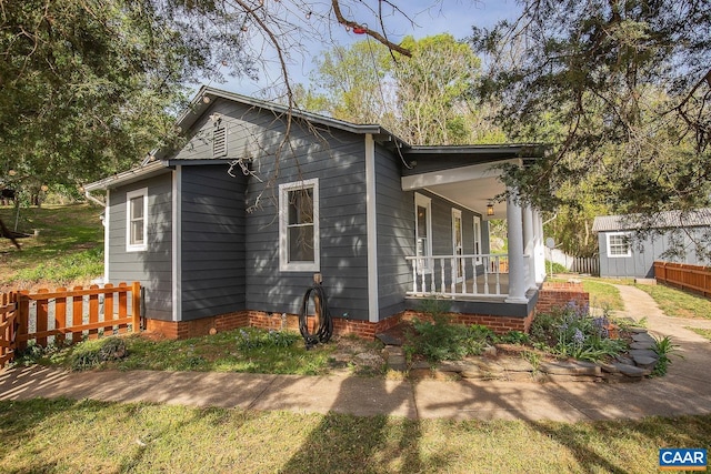 exterior space featuring fence, an outdoor structure, a porch, and a storage shed