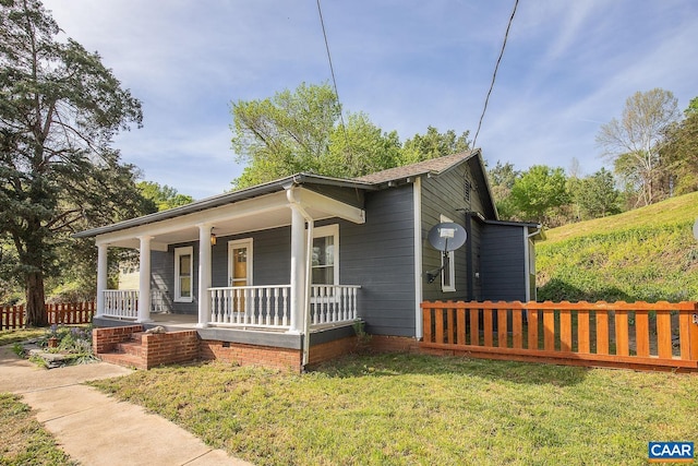 view of front facade with fence, covered porch, and a front yard