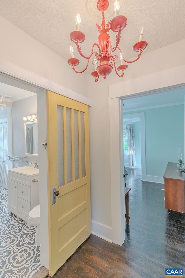 hallway with a sink, baseboards, dark wood-type flooring, and a chandelier