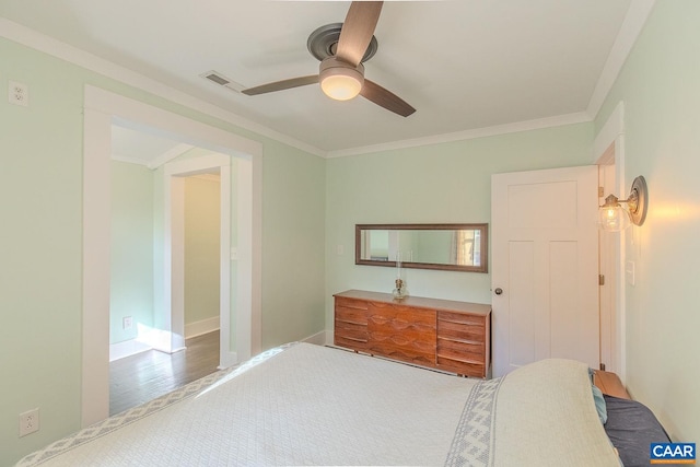 bedroom featuring crown molding, a ceiling fan, baseboards, wood finished floors, and visible vents