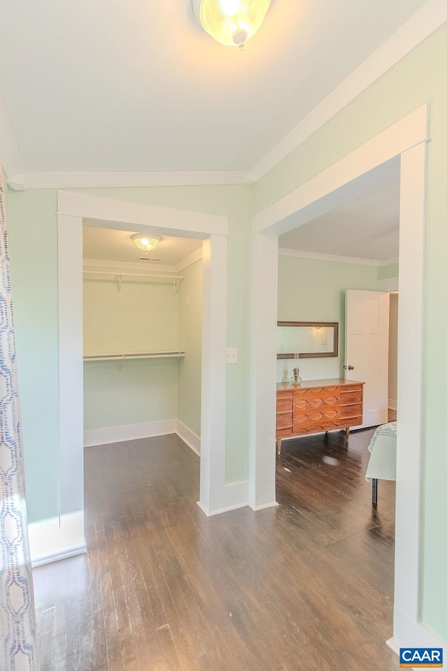 hall with baseboards, ornamental molding, and wood finished floors