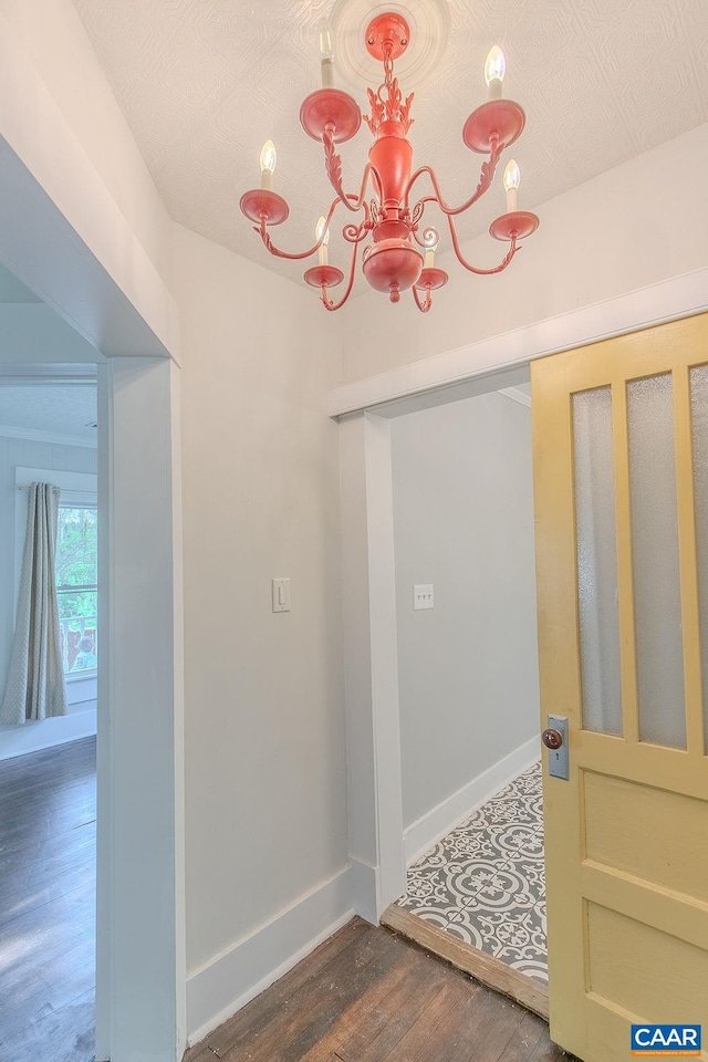 hall with baseboards, an inviting chandelier, and wood finished floors
