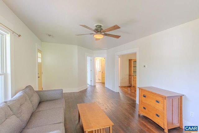 living room featuring baseboards, visible vents, a ceiling fan, and dark wood-type flooring