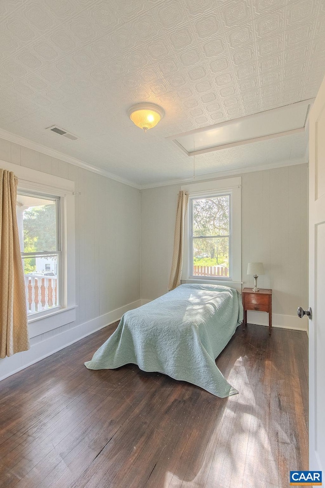 bedroom with visible vents, multiple windows, attic access, and hardwood / wood-style floors