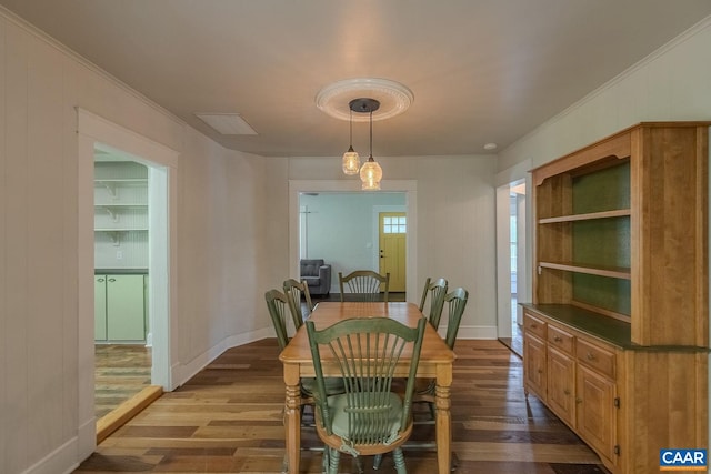 dining room with baseboards, ornamental molding, and dark wood finished floors