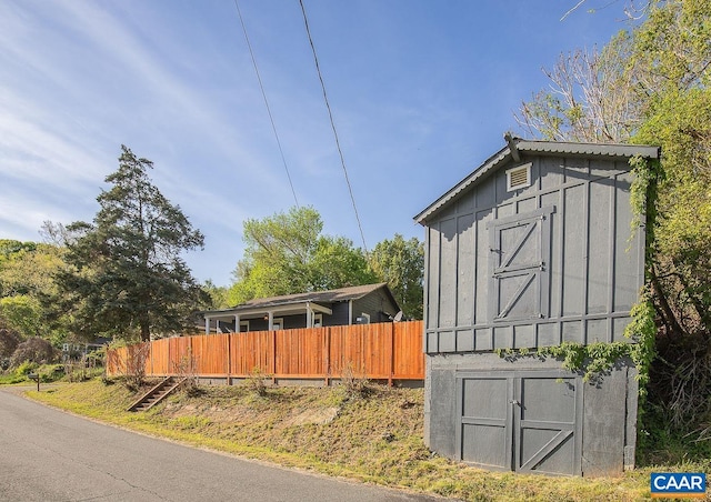 view of home's exterior with board and batten siding, fence, an outdoor structure, and a storage unit