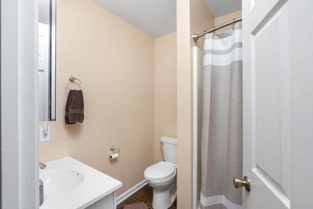 bathroom featuring vanity, hardwood / wood-style floors, curtained shower, and toilet