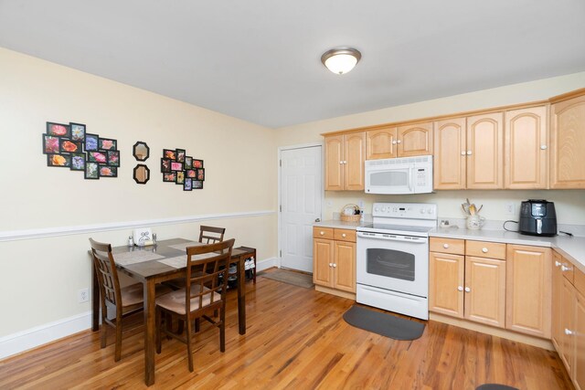 kitchen with light brown cabinetry, white appliances, and light hardwood / wood-style floors