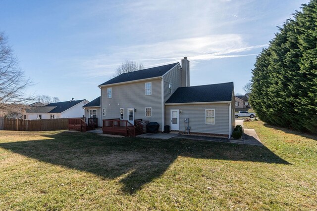 rear view of house featuring a wooden deck, a lawn, and a patio